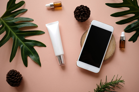 natural cosmetic cream , serum, skincare blank bottle packaging with leaves herb, wood . bio organic product.beauty and spa concept. online shopping with mobile phone and credit card.の写真素材