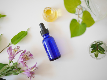 natural skincare bottle container and  organic green leaf , flowers ingredients with the laboratory glassware on white background. Home made remedy and beauty product concept.の写真素材