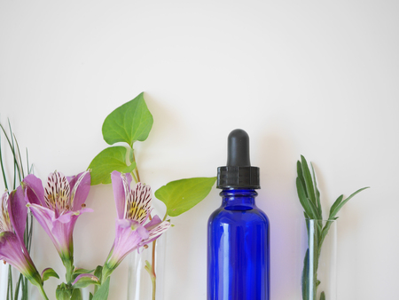 natural skincare bottle container and  organic green leaf , flowers ingredients with the laboratory glassware on white background. Home made remedy and beauty product concept.の写真素材