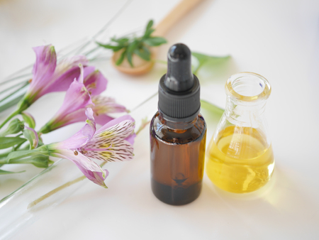 natural skincare bottle container and  organic green leaf , flowers ingredients with the laboratory glassware on white background. Home made remedy and beauty product concept.の写真素材