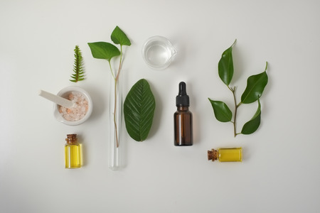 Cosmetic package containers with green leaves, pink salt,herbal . natural  organic beauty product concept mock up. Blank bottle for label own branding skincare. isolated white background.top view.の写真素材
