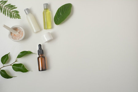Cosmetic package containers with green leaves, pink salt,herbal . natural  organic beauty product concept mock up. Blank bottle for label own branding skincare. isolated white background.top view.の写真素材