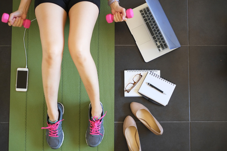 female workout and work at home to balance life . active fitness to play on healthy and strong body with laptop , mat,weight ,mobile phone and sneakers.の写真素材