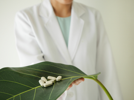 scientist or doctor making herbal medicine with herb leaves , capsule, tablets.hands.の写真素材