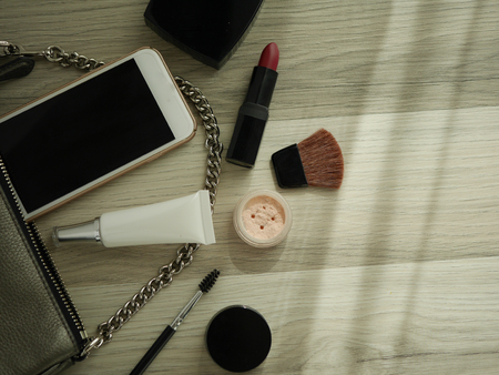 cosmetic  makeup product and skincare  flat lay. top view on light wood background . modern black accessories set bag with smart mobile phone.の写真素材