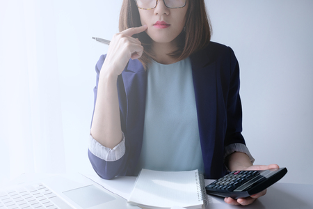 beautiful young business woman working in the office or home with paperwork calculator laptop and computer.の写真素材