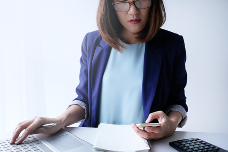 beautiful young business woman working in the office or home with paperwork calculator laptop and computer.の写真素材