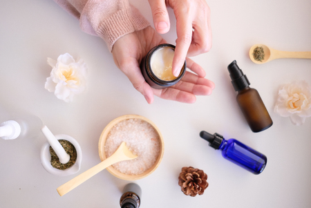 hand with cosmetic cream lotion .Beauty skincare background .Products with flower ,leaves . pink minimal concept table top view, flat lay.の写真素材