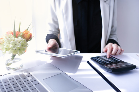 beautiful young business woman working in the office or home with paperwork calculator laptop and computer.の写真素材