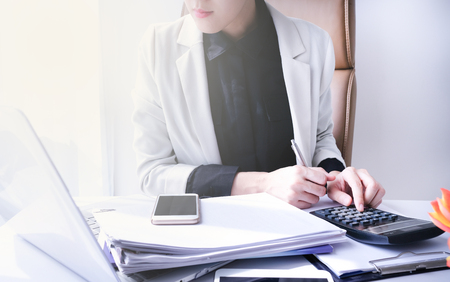 beautiful young business woman working in the office or home with paperwork calculator laptop and computer.の写真素材
