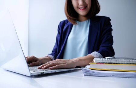 beautiful young business woman working in the office or home with paperwork calculator laptop and computer.の写真素材