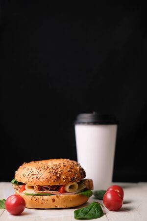 Delicious classic blt sandwiches with ham, cheese, bacon, tomatoes. Breakfast and fast food meal box set with drink on isolated black background wooden and text copy space.の写真素材