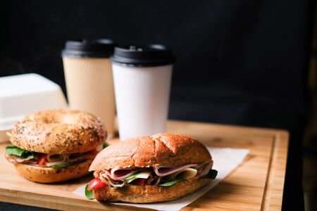 Delicious classic blt sandwiches with ham, cheese, bacon, tomatoes. Breakfast and fast food meal box set with drink on isolated black background wooden and text copy space.の写真素材