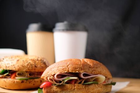 Delicious classic blt sandwiches with ham, cheese, bacon, tomatoes. Breakfast and fast food meal box set with drink on isolated black background wooden and text copy space.の写真素材