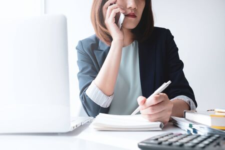 beautiful young business woman working in the office or home with paperwork calculator laptop and computer.の写真素材