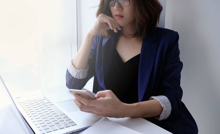 beautiful young business woman working in the office or home with paperwork calculator laptop and computer.の写真素材