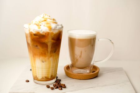 Ice coffee in the glass topped whipping cream with coffee beans. Cold summer drink on wooden background and copy space. Advertising for caramel mocha and chocolate beverage for the cafe.の写真素材