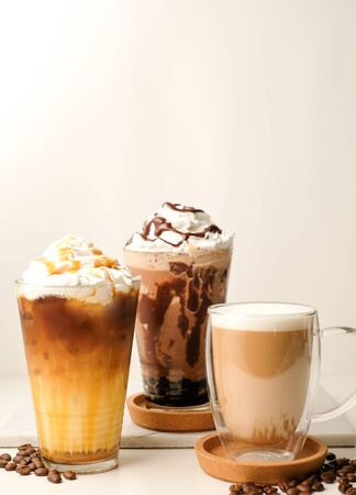 Ice coffee in the glass topped whipping cream with coffee beans. Cold summer drink on wooden background and copy space. Advertising for caramel mocha and chocolate beverage for the cafe.の写真素材