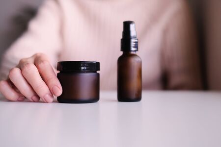 hand with cosmetic cream lotion .Beauty skincare background .Products with flower ,leaves . pink minimal concept table top view, flat lay.の写真素材