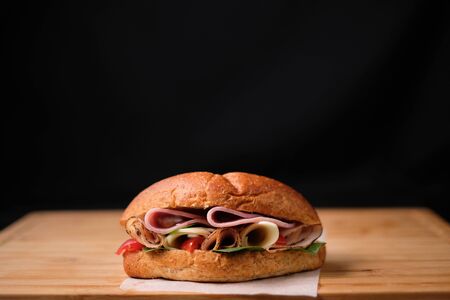 Delicious classic blt sandwiches with ham, cheese, bacon, tomatoes. Breakfast and fast food meal. on isolated black background wooden and text copy space.の写真素材