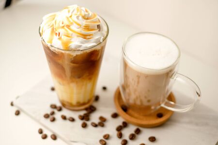 Ice coffee in the glass topped whipping cream with coffee beans. Cold summer drink on wooden background and copy space. Advertising for caramel mocha and chocolate beverage for the cafe.の写真素材