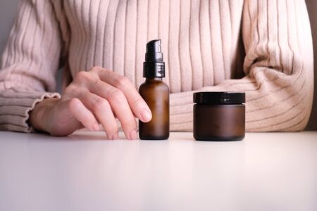 hand with cosmetic cream lotion .Beauty skincare background .Products with flower ,leaves . pink minimal concept table top view, flat lay.の写真素材
