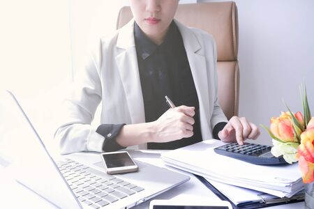 beautiful young business woman working in the office or home with paperwork calculator laptop and computer.の写真素材
