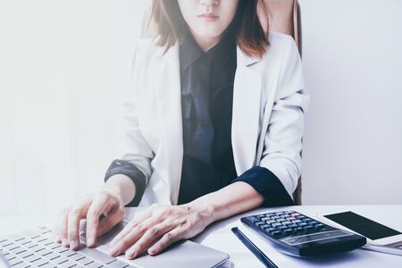 beautiful young business woman working in the office or home with paperwork calculator laptop and computer.の写真素材