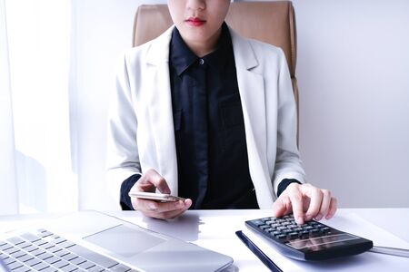 beautiful young business woman working in the office or home with paperwork calculator laptop and computer.の写真素材