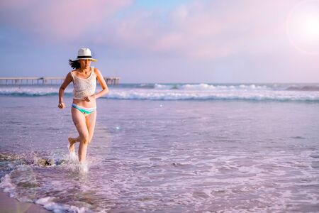young woman on sunset beach and joyful running . happy summer vacation. positive lifestyle and relaxing travel. nature recreation.の写真素材