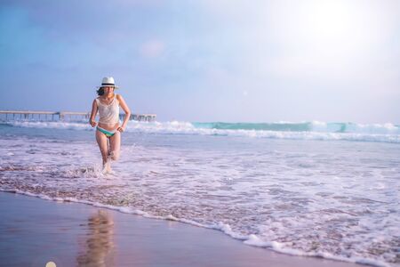 young woman on sunset beach and joyful running . happy summer vacation. positive lifestyle and relaxing travel. nature recreation.の写真素材