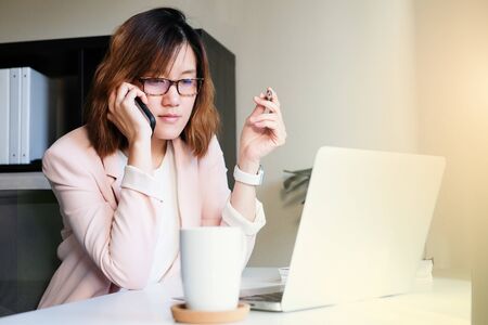 asian adult entrepreneur work on laptop and mobile phone with paperwork in the smart officeの写真素材