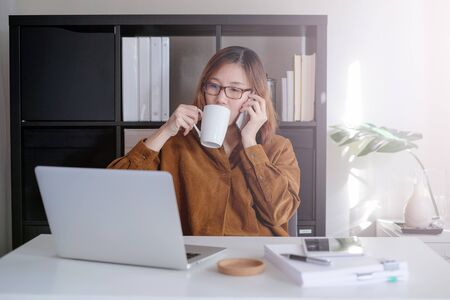asian adult entrepreneur work on laptop and mobile phone with paperwork in the smart officeの写真素材
