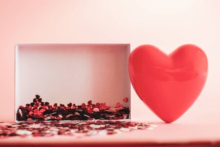 Valentine's Day background . red gloss heart with confetti on pink pastel background with copy space. wedding wallpaper.の写真素材