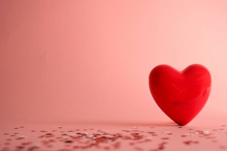 Valentine's Day background . red gloss heart with confetti on pink pastel background with copy space. wedding wallpaper.の写真素材