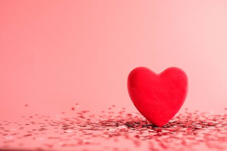 Valentine's Day background . red gloss heart with confetti on pink pastel background with copy space. wedding wallpaper.の写真素材