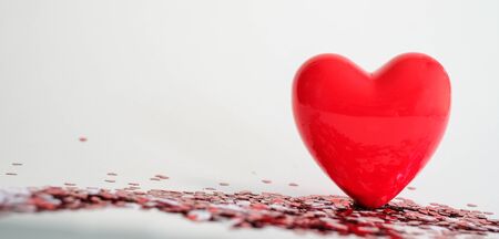 Valentine's Day background . red gloss heart with confetti on pink pastel background with copy space. wedding wallpaper.の写真素材