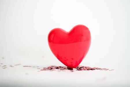 Valentine's Day background . red gloss heart with confetti on pink pastel background with copy space. wedding wallpaper.の写真素材