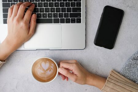 woman hold coffee cup while working on her laptop. happy morning concept. flat lay.