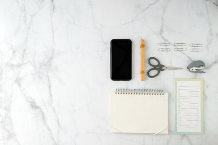 Flat lay workspace with smartphone, pen, notebook, planner and stationary with copy space on marble table. background. Top view. modern style.の写真素材