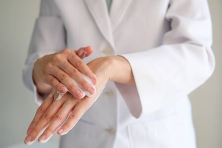 doctor wash hands with the foam soap to clean virus, bacteria and germ. white uniform background. close up. Washing is the way to prevent spreading covid19.の写真素材