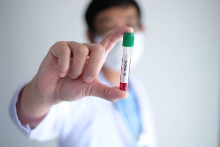 doctor wearing respirator mask holding positive blood test result for the new pandemic outbreak of the Coronavirus, covid 19 .の写真素材