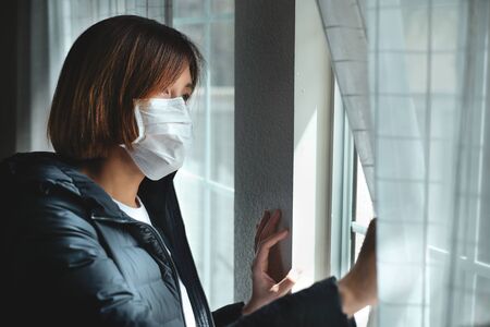 woman stay and safer at home looking at the window for self quarantine to stop the corona virus, covid19 pandemic outbreak .の写真素材