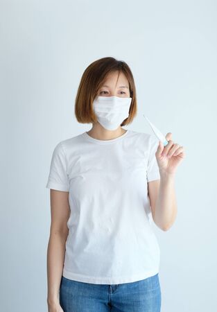 woman wearing mask reading thermometer and have fever get sick from corona virus, covid19, flu symptom .の写真素材