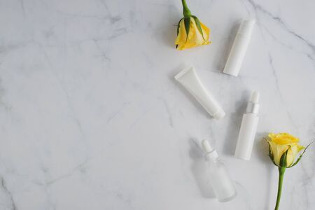 cosmetic skincare packaging . beauty product mock up on luxury white marble with yellow rose.の写真素材