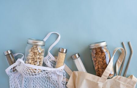 zero waste lifestyle .cotton net bag with nut, spice in sustainable glass jar and reusable straw on blue background flat lay.plastic free.の写真素材
