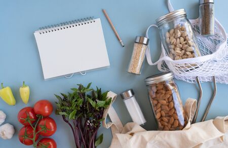 list and notebook for zero waste lifestyle .cotton net bag with fresh vegetables and sustainable glass jar on blue background flat lay.plastic free for groceries product shopping and delivery.の写真素材