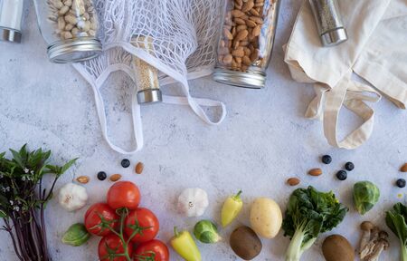zero waste lifestyle .cotton net bag with fresh vegetables and sustainable glass jar on cement background flat lay.plastic free for groceries product shopping and delivery. food and healthy diet.の写真素材