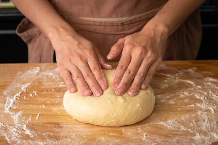 chef knead the bread dough on wooden table in a bakery.の写真素材