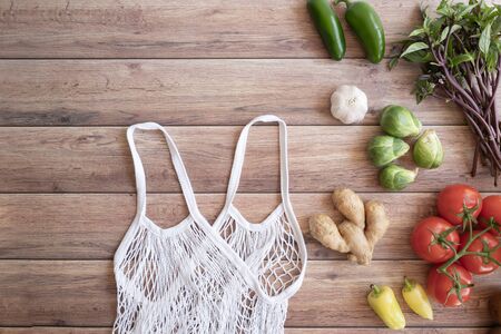 zero waste lifestyle .cotton net bag with fresh vegetables on wooden table flat lay.plastic free for groceries product shopping and delivery.の写真素材